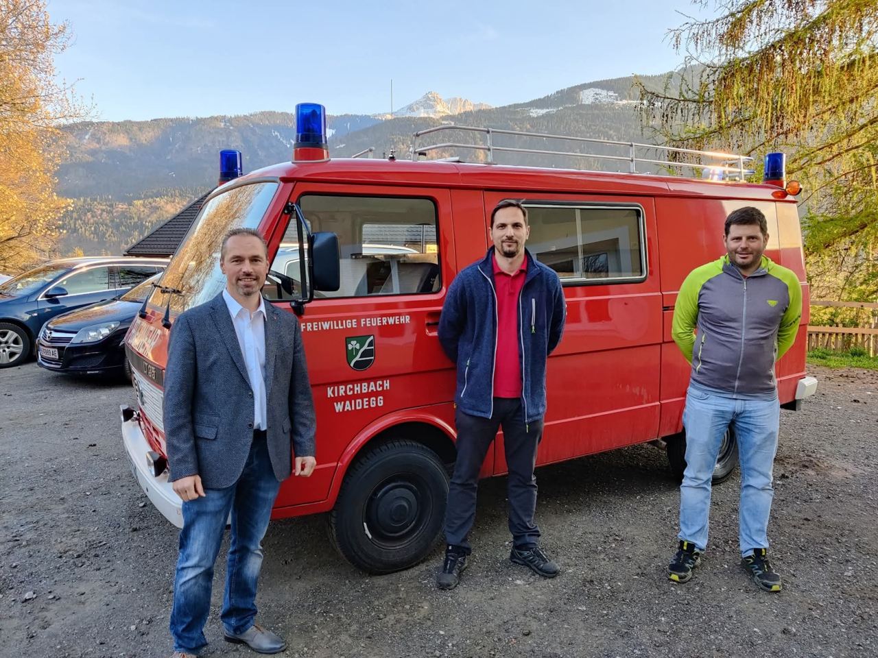 Verabschiedung des alten KLF VW LT der FF Waidegg: drei Personen vor dem roten Fahrzeug mit Blaulicht
