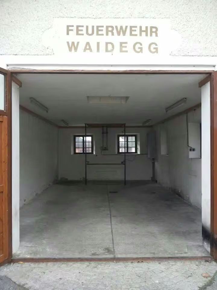 Leere Fahrzeughalle mit der Aufschrift Feuerwehr Waidegg am Tag des Umzugs